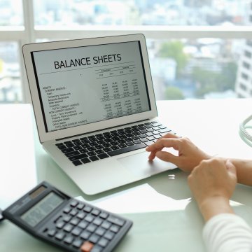 sage accounting software woman on laptop at the office calculator on the desk